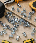 50 Pack Jack Nuts 1/4-20 Threaded Inserts Petal Nuts And Blind Fasteners For Plastic And Metal Projects Zinc Plated Steel And Aluminum Alloy Dowels Screw Anchors For Hollow Plates Pipes Sheets And More, scattered on a wooden surface with tools in the background.