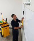 Janitor with cleaning cart, featuring Heavy Duty 24 Gallon Front Zippered Vinyl Replacement Bag For Industrial Janitorial Carts Yellow Waste Linen And Trash Collection Durable Front Loading Bag For Commercial Cleaning Compatible With Rubbermaid Commercial Carts, mopping window in office.
