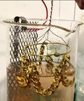 Jewelry in High Concentration 24K Gold Plating Bath Solution 100ml being electroplated, showing gold chain in beaker setup.