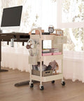 3 Tier Rolling Cart With DIY Pegboard Panels, Metal Utility Cart On Wheels Featuring Adjustable Front Or Side Pegboards, Includes 2 Hanging Baskets And 4 Hooks, Super Handy For Craft Room Kitchen Office Bathroom Organization In Khaki next to desk in office