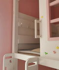 White children's bunk bed with pink accents and decorative stickers in a pink room