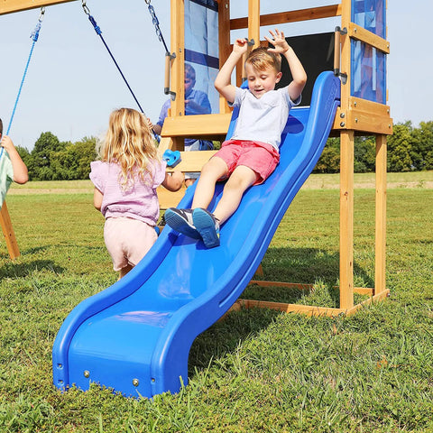 Children playing on a blue slide attached to a wooden play structure in a grassy field.
