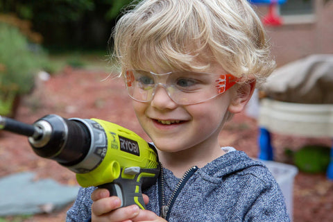 Child wearing Kids Safety Glasses ANSI Z87.1 EN166 Certified Impact Resistant Clear Lenses holding a drill
