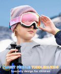 Child wearing Kids Ski Goggles For Boys And Girls 3 To 12 With Anti Fog UV400 Protection, pink frame, snowy background.