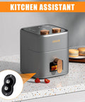 Grey kitchen appliance with toast slot on counter, orange accents, "KITCHEN ASSISTANT" text, black caster wheel inset