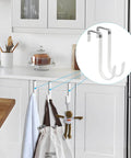 Over-cabinet door hooks in a kitchen holding towels and a bag