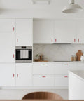 Modern kitchen with white cabinets featuring Six Pack Adjustable Cabinet Handles In Red Aluminum For Kitchen Drawers And Cabinets.