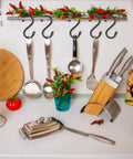 Kitchen countertop with utensils, knives in a wooden block, spaghetti canister, chili peppers on hooks, and cutting board.