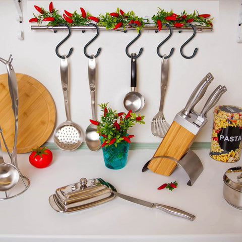 Kitchen countertop with utensils, knives in a wooden block, spaghetti canister, chili peppers on hooks, and cutting board.