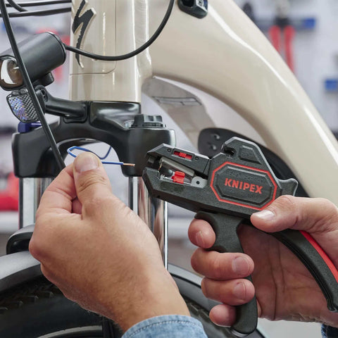 Person using Knipex Automatic Wire Stripper 10-24 AWG, 7.25 Inch Length on a bicycle cable for precise stripping.