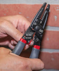 Kurve Wire Stripper Crimper Cutter Multi Tool For 10-26 AWG Solid And 12-28 AWG Stranded Wire in use against a brick wall