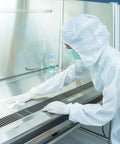 Person cleaning lab surface with Lint Free 4x4 Wipes 1200 Pcs Cellulose Polyester Blend For Lab Pharma, wearing protective gear.