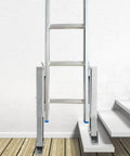 Ladder Leveler Pair For Extension Ladders installed on uneven wooden and stair surface, showing adjustable steel anti-slip pattern poles.