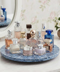 12.6 inch mother of pearl lazy susan turntable with blue starburst design holding various perfumes on countertop.