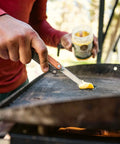Person using Leatherman Bond 14 In 1 Lightweight Multi Tool for Camping Hiking and Everyday Carry EDC Made in USA to slice butter on grill.