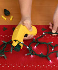 Using The Complete LED Christmas Holiday Light Set Repair Tool To Fix LED Light Sets on a red table.