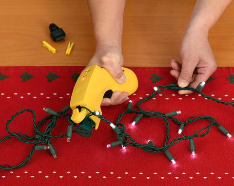 Using The Complete LED Christmas Holiday Light Set Repair Tool To Fix LED Light Sets on a red table.