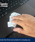 Flents Lens Wipes white pre-moistened wipe in hand wiping laptop surface; logo visible