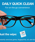 Hand holding eyeglasses with a cleaning wipe package, demonstrating the Lens Wipes And Microfiber Cloths Value Kit For Eyeglasses And Screens.