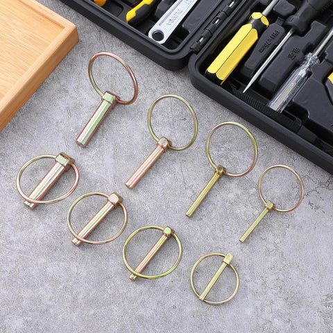 Heavy Duty Lynch Pin Kit 60 Pc Assortment For 3 Point Hitch Pins Trailer Pins For Farm Tractors Trailers Trucks And Mowers Carbon Steel Self Locking Pins For Secure And Durable Heavy Equipment Use, pins displayed on a table with tools in background.