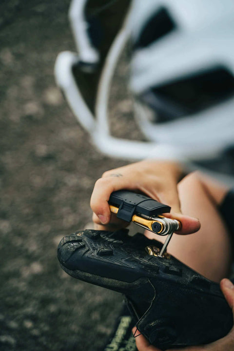 Crankbrothers Multi Tool M10 Gold Compact Trailside Essential in use with bike repair, showing gold tool body and ergonomic grips.