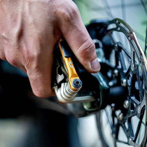 M17 Gold Bicycle Multi Tool in hand during bike repair, showing hex and spoke wrenches, close-up on ergonomic grips