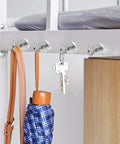 Magnetic hooks holding a bag, keys, and an umbrella under a metal frame, showcasing utility organization with simple installation.