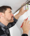 Man using compact magnetic 3 inch mini level with two bubbles for aligning curtain rod on metal surface, showcasing hands-free use.