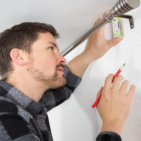 Man using compact magnetic 3 inch mini level with two bubbles for aligning curtain rod on metal surface, showcasing hands-free use.