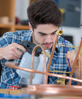 Man using AWS BAg7 Silver Brazing Rods Flux Coated Solder Kit Pro Grade for copper pipe repair, focused on brazing process