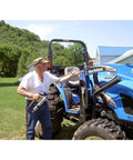 Man using Heavy Duty Pneumatic Grease Gun With 30 Inch High Pressure Hose And 6000 PSI Power on blue tractor in farm setting
