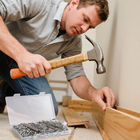 Man installing skirting boards with a hammer, using 400pcs Double Head Skirting Nails with 4 Tools - Invisible Seamless Baseboard Screws for Solid Wood Trim.