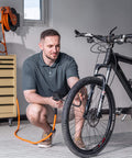 Man using Retractable Air Hose Reel With 180 Degree Swivel Bracket For Ceiling Or Wall Mount Three Eighths Inch By Fifty Foot Hybrid Hose on bicycle tire