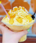 Mango snow ice dessert in clear disposable cup with two spoons