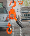 Manual Lever Chain Hoist 1/2 Ton 1100 Lbs Capacity 5 Ft in garage with open car trunks, showcasing orange G80 chain and 360° hook