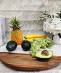 Large Marble And Acacia Wood Lazy Susan Turntable Rotating Serving Tray with assorted fruits and flowers on a dining table.