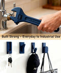 Hand using blue 3D printed wrench on faucet, showcasing strength and utility; wall hooks with keys and hat displayed below.