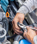 Hands using pliers on spring band type hose clamp in engine, showing installation process in a mechanical setting.