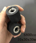 Hand holding two black rubber 6800zz bearings, size 10x30x30mm, for mechanical systems and automation.