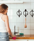 Three-Piece Knife, Fork and Spoon Kitchen Hook - Metal Wall Hanging in modern kitchen with woman cleaning
