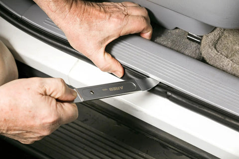 Person using Compact Double End Metal Skin Wedge Prybar Tool By ARES for car panel removal, ultra thin 23 gauge ends visible.