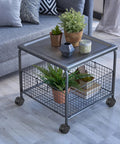 Metal table with wire basket and decor items on top, featuring 2 Inch Nylon Caster Wheels With Brake, 5/16-18 Threaded Stem UNC Coarse Thread.