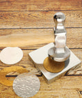Polished metal stamping tool on wooden surface with embossed metal discs