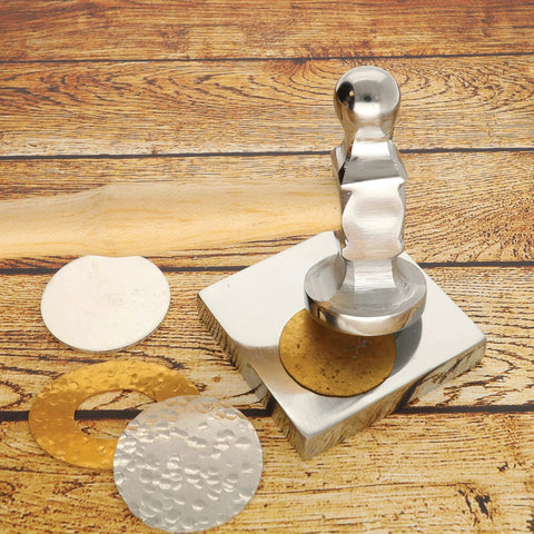 Polished metal stamping tool on wooden surface with embossed metal discs