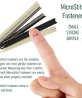Finger holding MicroStitch fastener from Ultra Fine Needle Tagger Kit with black, white fasteners for fabric repairs.