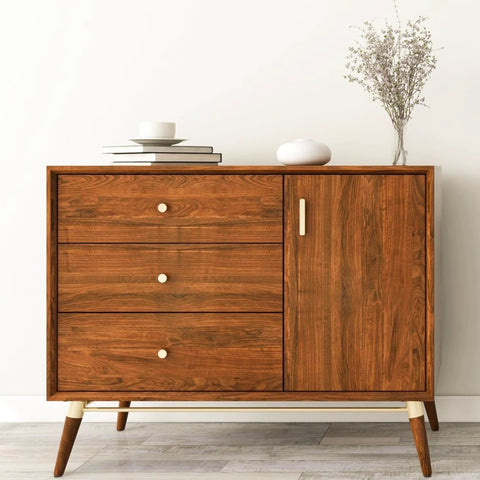 Wooden dresser featuring 3 drawers and a cabinet door, decorated with minimalist items on top in a modern interior setting.