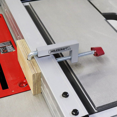 Milescraft universal fence clamp with aluminum body and red adjustment knob on a metal saw fence