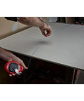 Milwaukee Chalk Line Reel Set F in use, showing a red reel with 100 ft blue line marking layout on a drywall surface.