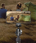 Two Pack Mini Ball Heads With 360 Degree Pan And 135 Degree Tilt Locking Knob Rubber Base Pad To Prevent Scratches Universal One Quarter Inch To Three Eighths Inch Screw Adapters Dual Cold Shoe Mounts For DSLR Cameras And Camcorders showing smartphone on tripod recording two people by tent