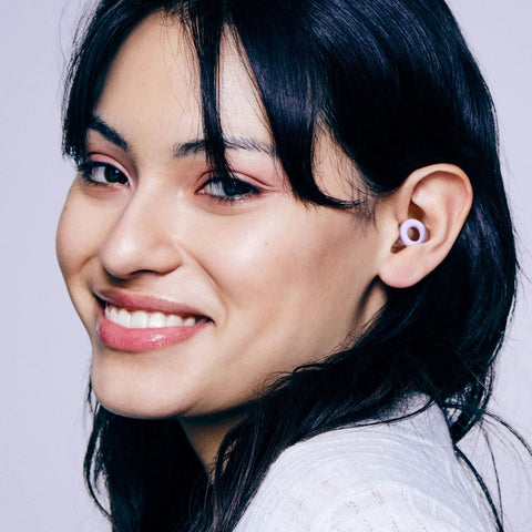 Woman wearing ultra comfortable, reusable ear plugs engineered for sleep, study, travel and quiet moments, M size visible.